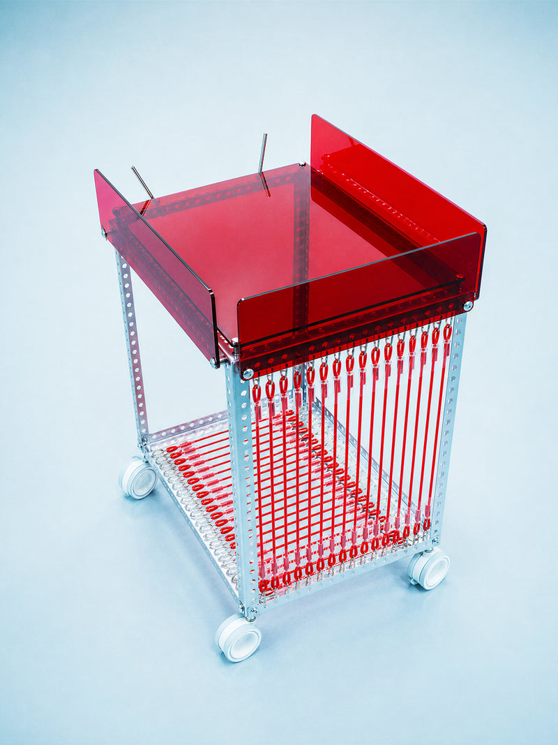 A modern rolling bar cart with a translucent red acrylic top and steel frame, shown on a light blue studio background.