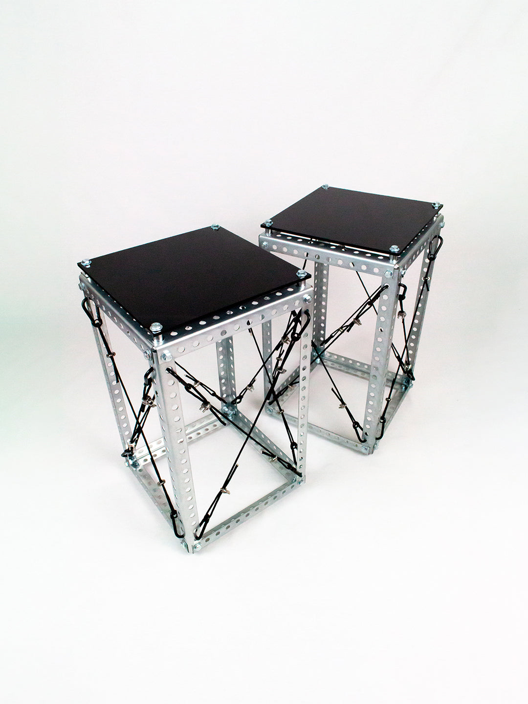 Side Table Set DP-001 pair shown at an angle, revealing the Diagrid steel frame's crossed cable bracing and black tabletops